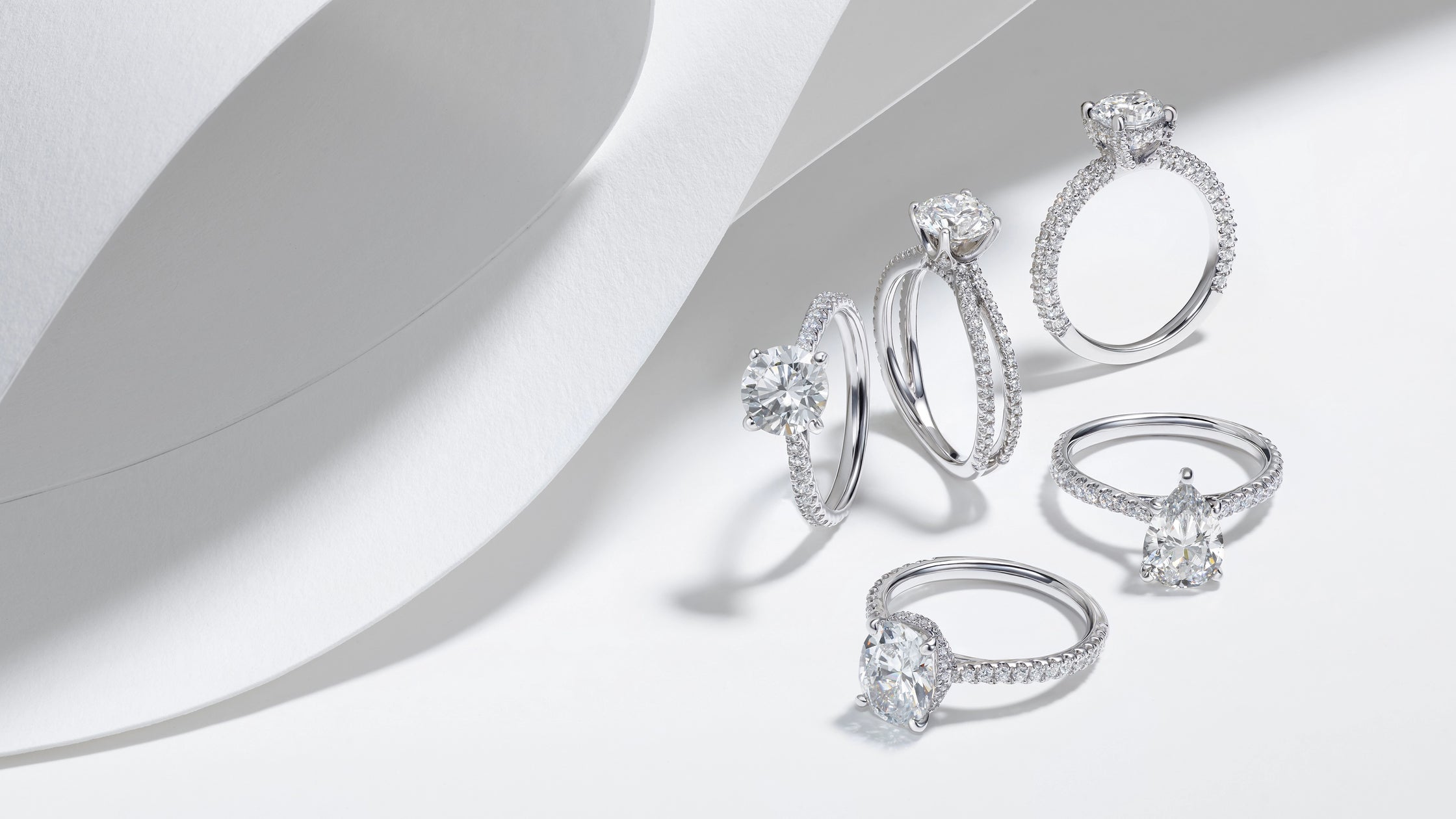 Five luxury ALTR created diamond engagement rings in white gold with round and pear-shaped center stones on a white background.