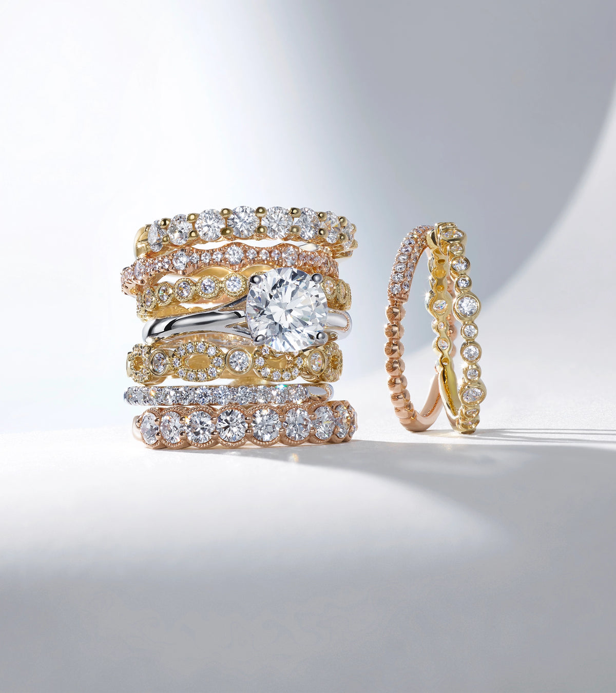 A stack of five mixed-metal ALTR lab-grown diamond wedding bands and engagement rings in gold and platinum.