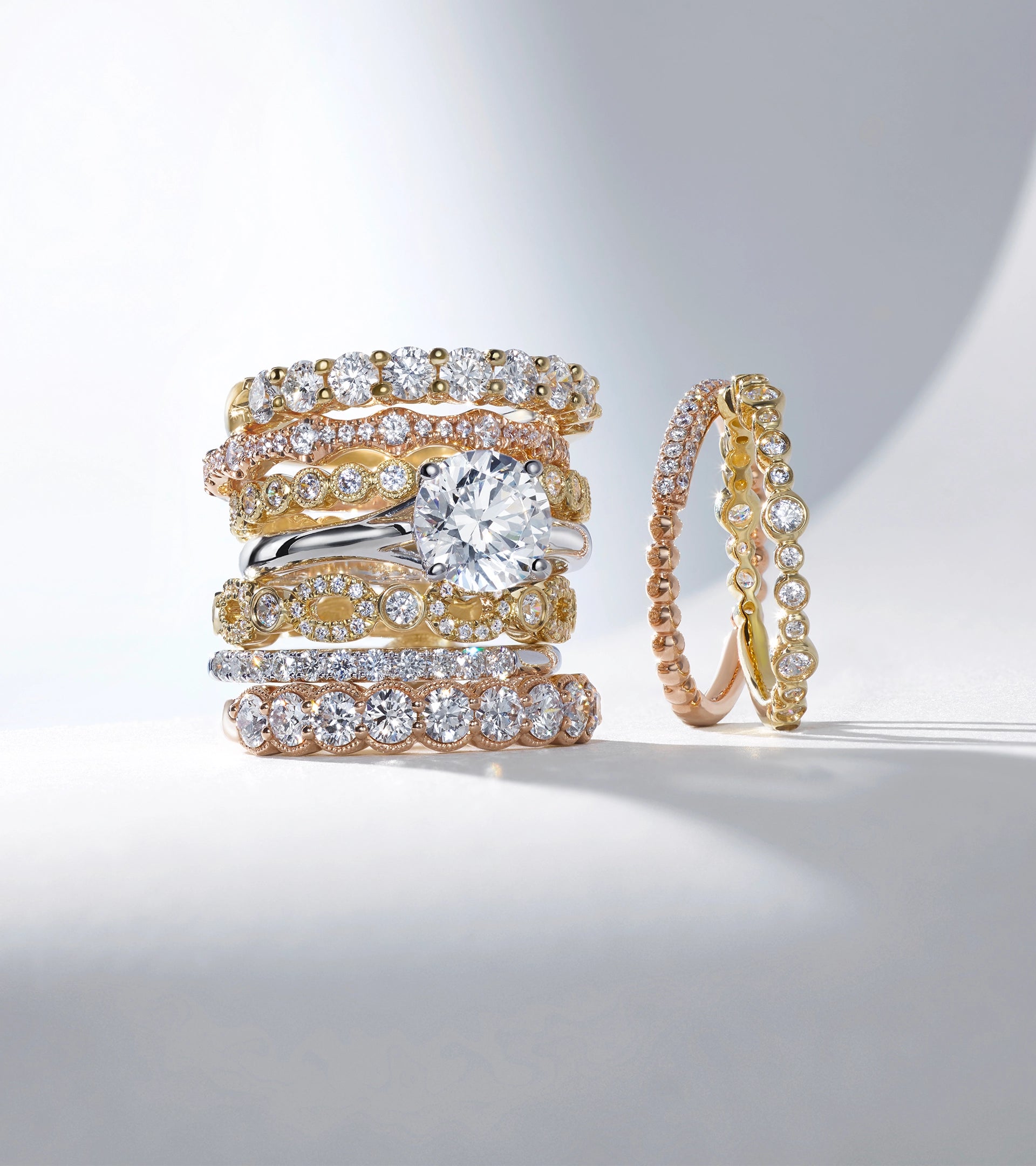 A stack of five mixed-metal ALTR lab-grown diamond wedding bands and engagement rings in gold and platinum.