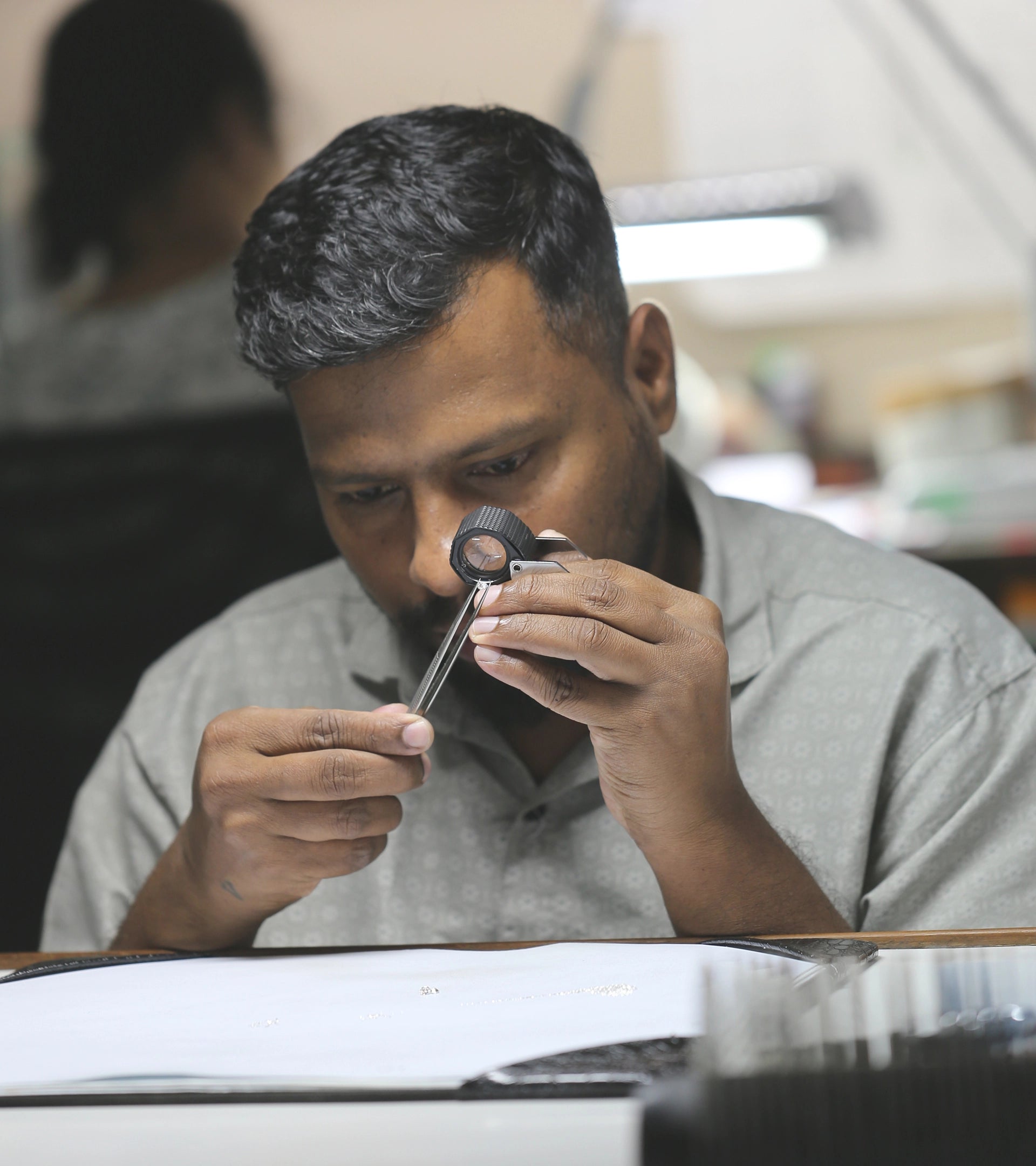 Master artisan using a jeweler's loupe to inspect an ALTR Created Diamond for quality craftsmanship at ALTR.