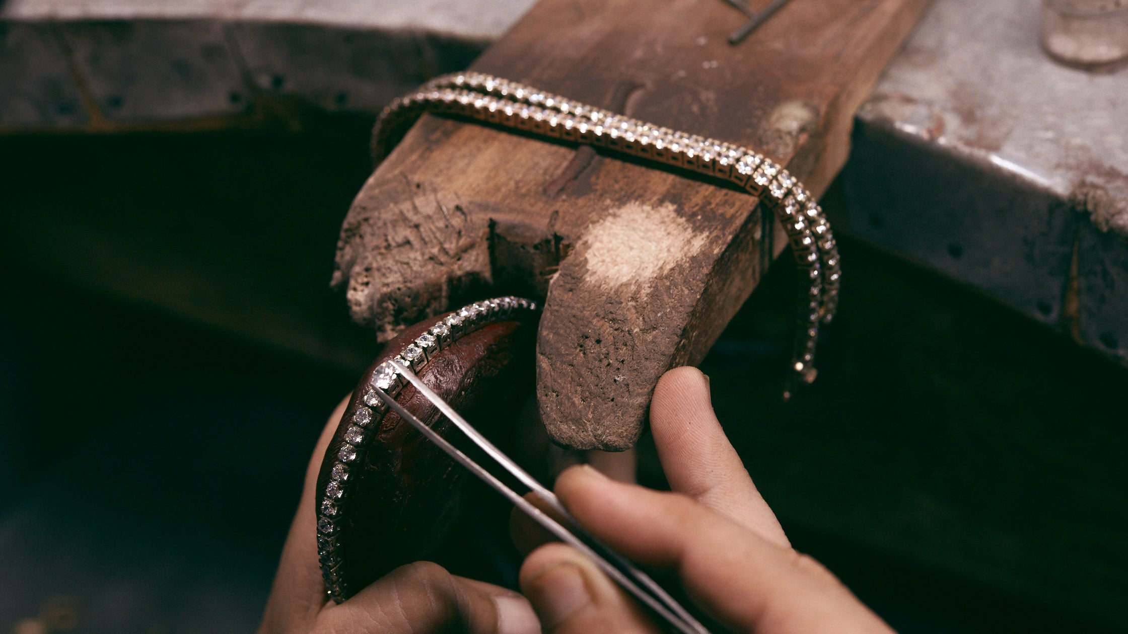 Artisan jeweler hand-setting a row of lab-grown diamonds into a tennis bracelet at a professional workbench showcasing precision craftsmanship