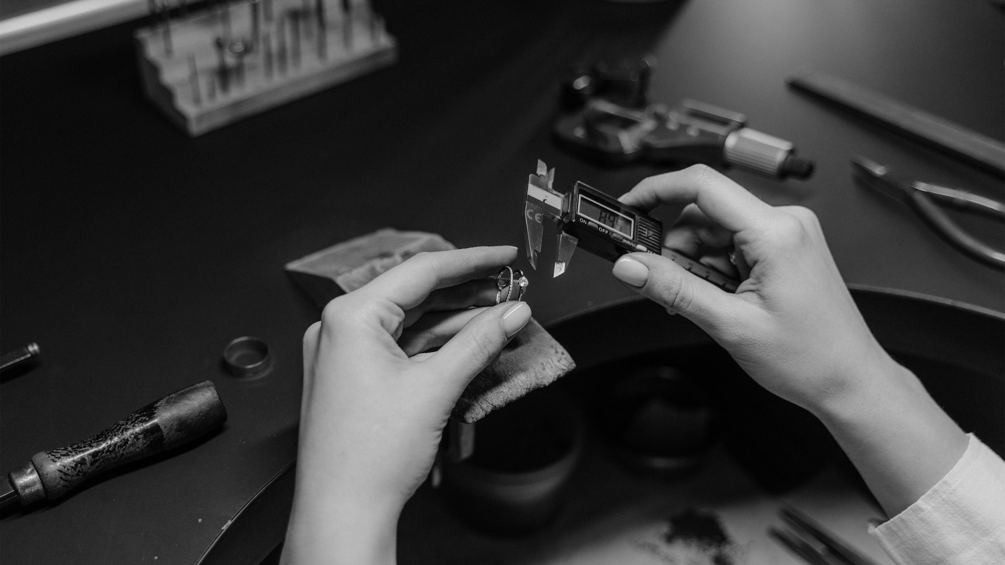 Close-up of an artisan using digital calipers to measure a lab diamond ring for precise manufacturing quality.