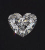 Macro video of a symmetrical heart-cut diamond centered against a dark, minimalist background. The diamond features a brilliant-cut faceting style that reflects white and spectral light as it rotates. The high-contrast setting emphasizes the diamond's clarity, sharp proportions, and the precision of the ALTR heart shape.